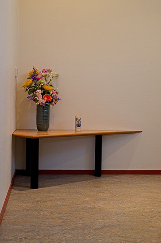 Hoek van de aula met een tafel en bloemen
